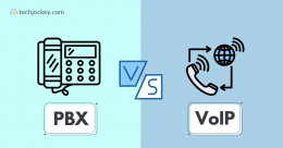 A comparison graphic with a PBX desk phone icon on a light blue background and a VoIP phone with global connectivity icon on a darker blue background, separated by a VS symbol, labeled PBX on the left and VoIP on the right, showing the contrast between traditional PBX and internet-based VoIP phone systems.